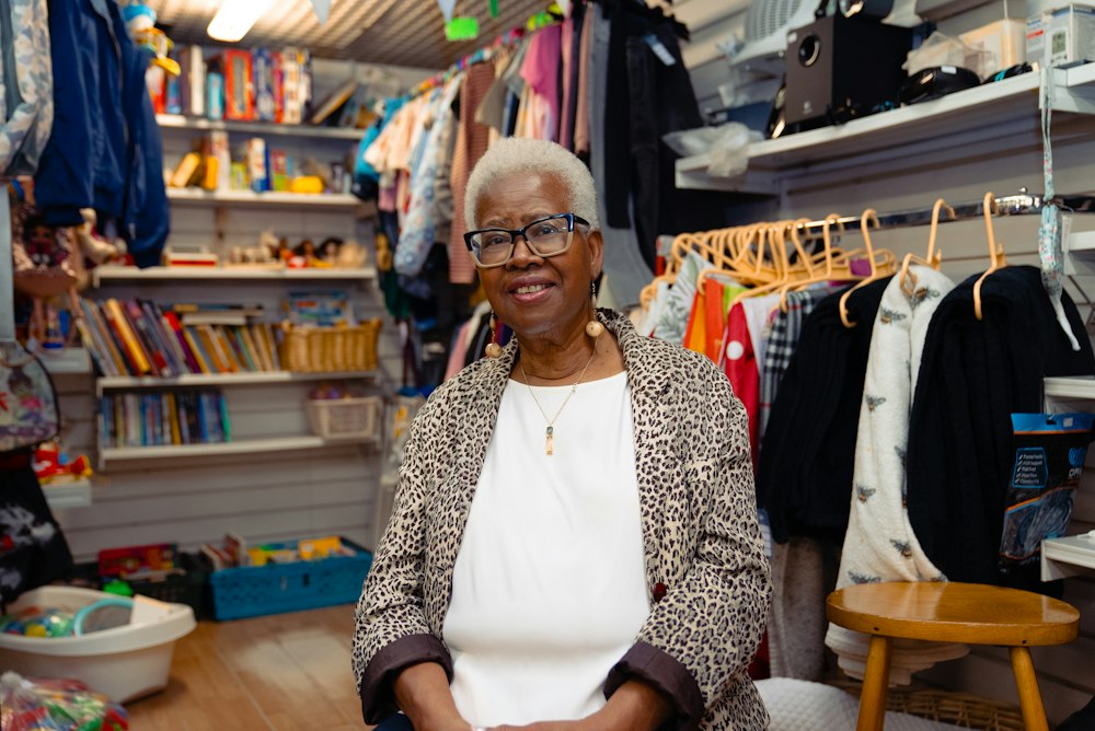 Dueña de una tienda de ropa sonriendo entre sus percheros